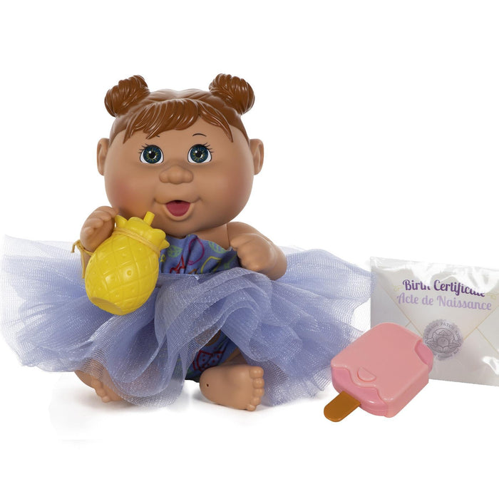 A 9-inch doll with hazel eyes and brown hair, wearing a purple outfit, sitting next to a yellow pineapple-shaped bottle and a pink popsicle.