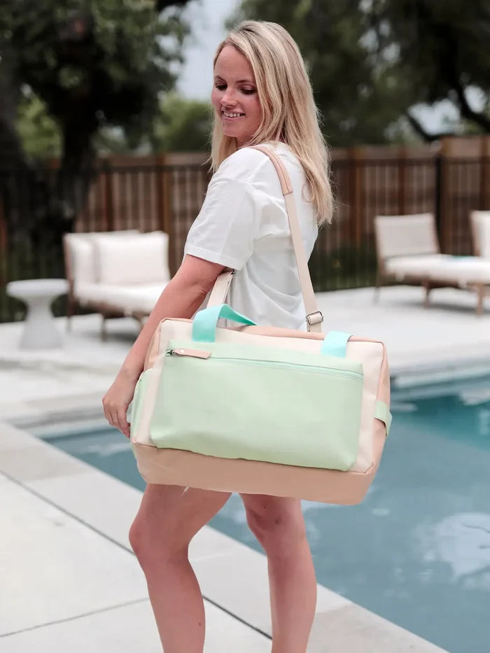 Stylish two-tone duffel bag in mint green and peach, perfect for gym or travel, featuring a comfortable shoulder strap.