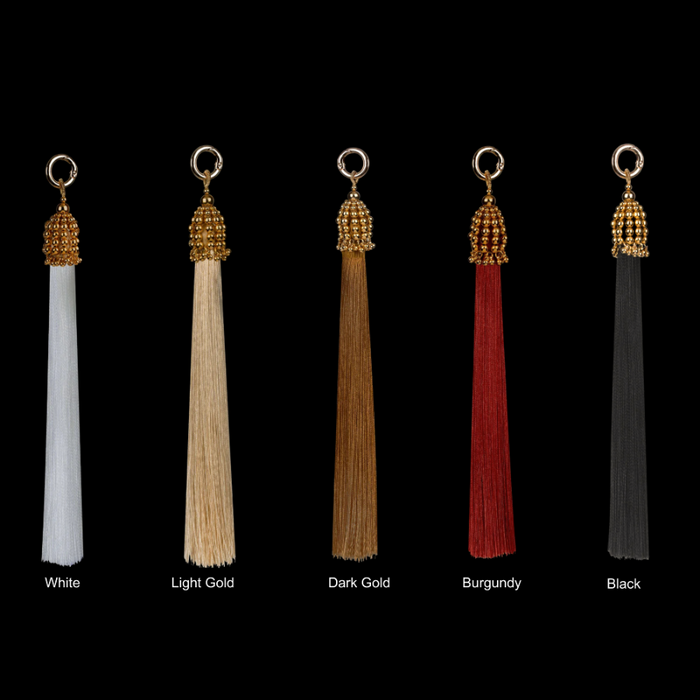 Set of five tassels in different colors with gold beads on a black background
