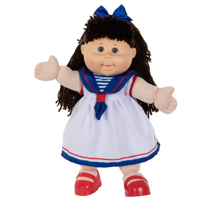 A 16-inch doll with brown hair, wearing a white sailor-style outfit with blue and red accents, and red shoes.
