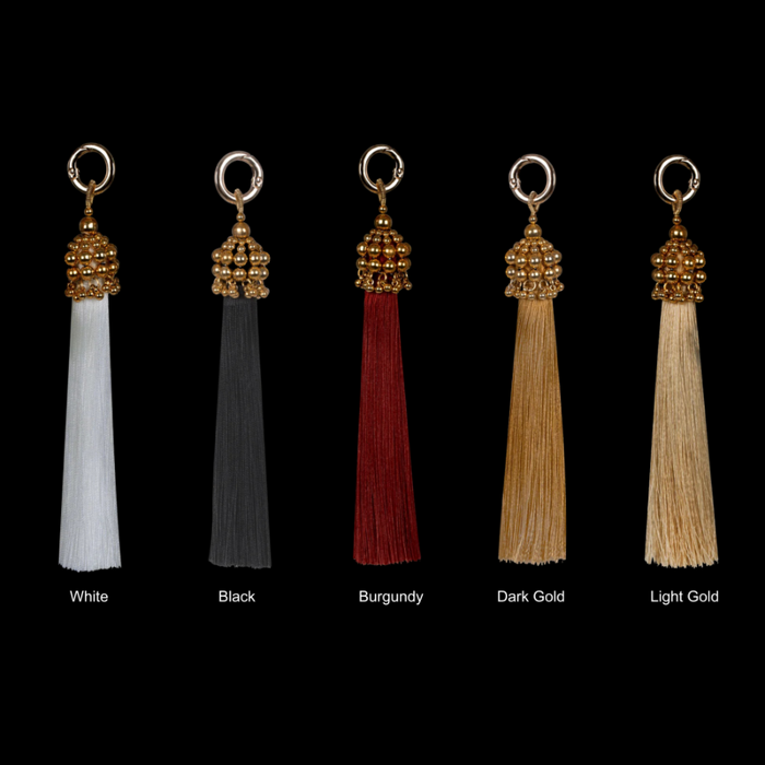 Set of five tassels in different colors with gold beads on a black background by Object&Dawn