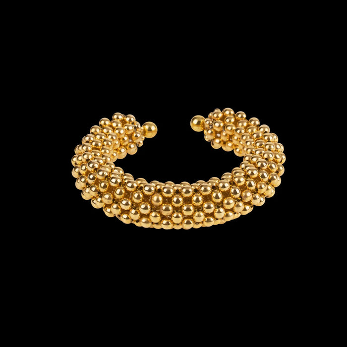 modular beaded wrist accessory in ivory, structured supple cuff with 22k gold wash polymer metal beads, ghost image front view