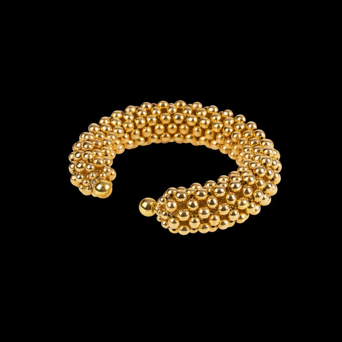 modular beaded wrist accessory in ivory, structured supple cuff with 22k gold wash polymer metal beads, ghost image diagonal view