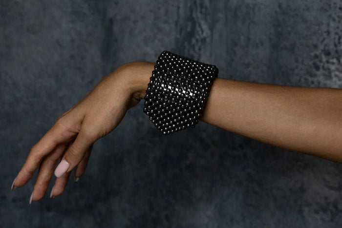 Object & Dawn beaded wrist accessory in ivory, structured supple cuff with polymer metal beads, ghost image side worn view