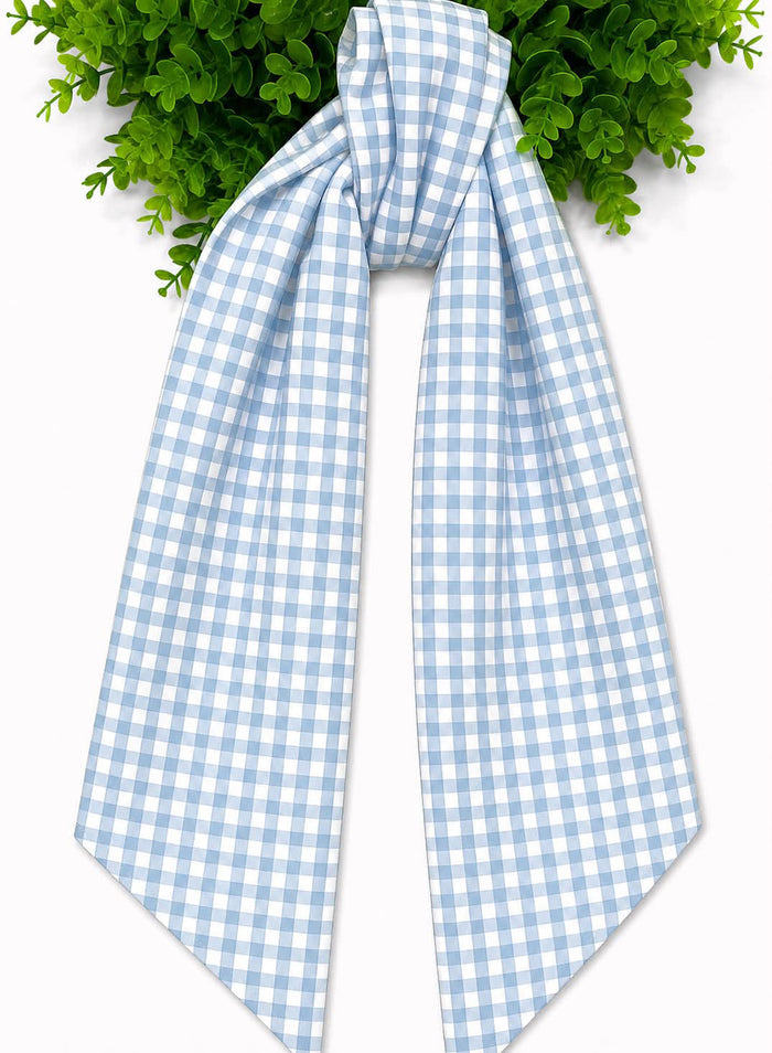 A light blue and white checked wreath sash tied in a knot and draped down, set against a white background with green foliage at the top.
