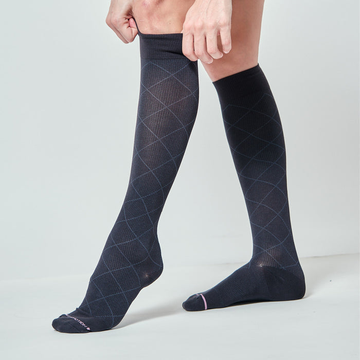 Knee-high compression socks with a diamond pattern, shown being worn on one leg.