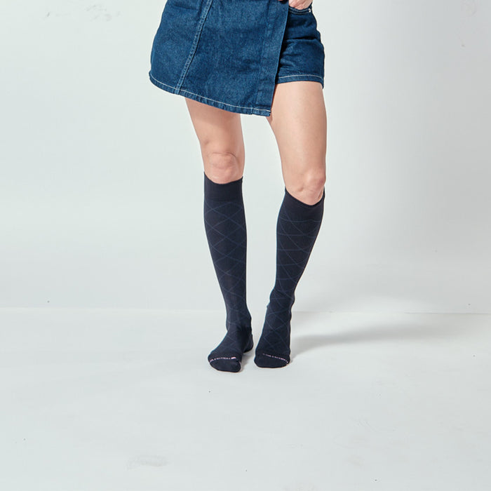Knee-high compression socks with a diamond pattern, worn with a denim skirt.
