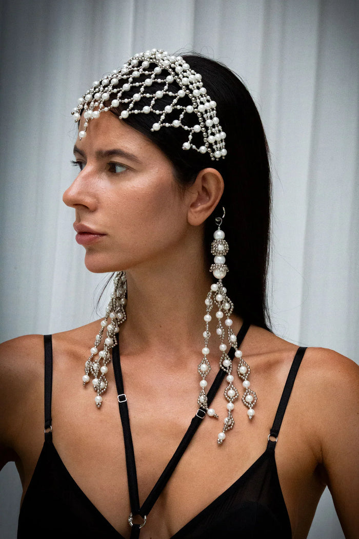 Woman wearing a black outfit with decorative freja headband against a grey background