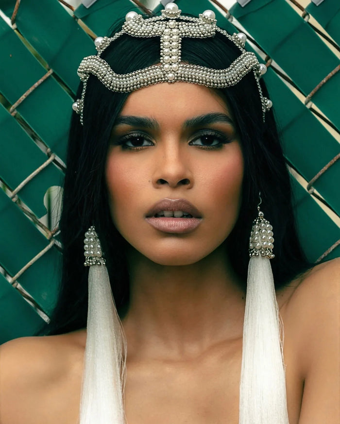 Woman wearing a decorative Khutulun Pearl headband by Object & Dawn against a dark green background