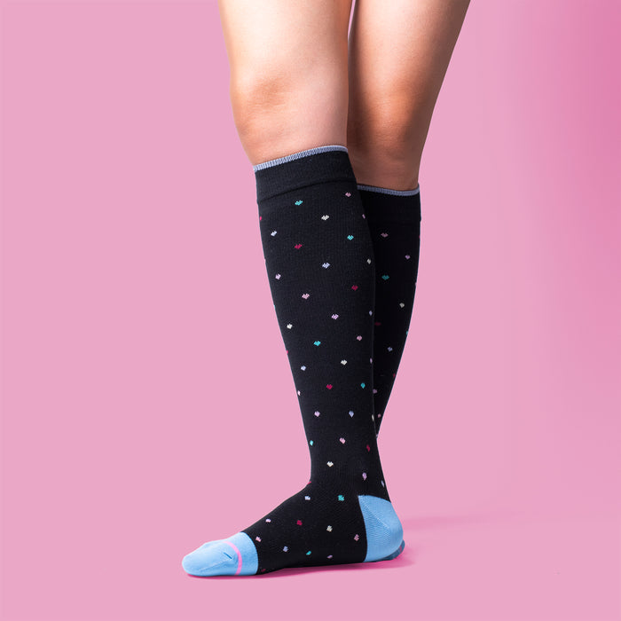 Knee-high black compression socks with colorful mini heart patterns and light blue toe and heel accents.