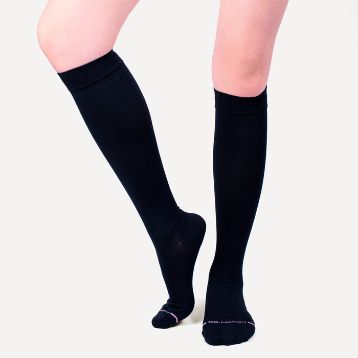 Knee-high black compression socks made of solid microfiber nylon, shown on a model's legs.