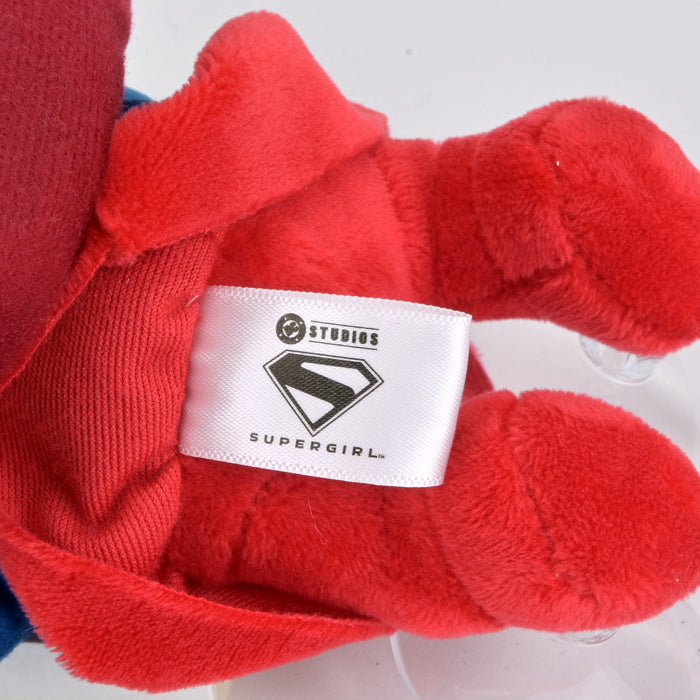 Supergirl plush window clinger featuring Supergirl logo and vibrant colors, designed to stick on windows for decorative display.