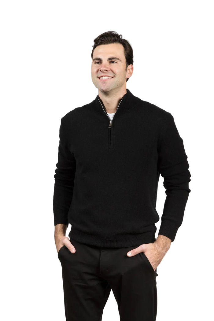 Man wearing a black quarter-zip sweater and black pants on a gray background