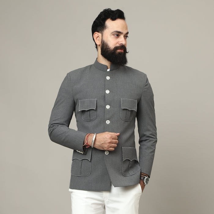 Man wearing a gray blazer and white pants against a plain background